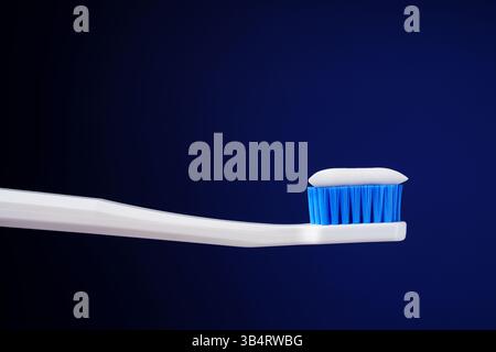 Das zahnärztliche Königskonzept. Hygiene. Professionelles Foto. Weiße Zahnbürste mit Zahnpasta auf dunkelblauem Hintergrund. Stockfoto
