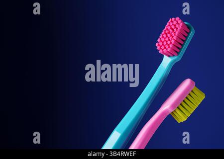 Es gibt einen Platz für Text. Zwei helle Plastikzahnbürsten auf dunkelblauem Hintergrund. Stockfoto