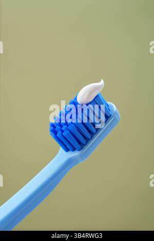 MINT-Hintergrund. Blaue Zahnbürste mit Zahnpasta auf grünem Hintergrund, Nahaufnahme. Stockfoto