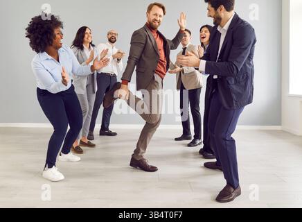 Geschäftsleute in Büroanzügen tanzen Spaß und feiern ihren Geschäftserfolg Stockfoto