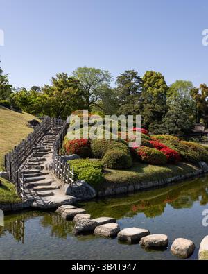 Blick auf die Gartenlandschaft von Okayama Korakuen mit Blick auf das Okayama Castle, mit traditionellem japanischem Teich und Ahornkirschblüten Stockfoto