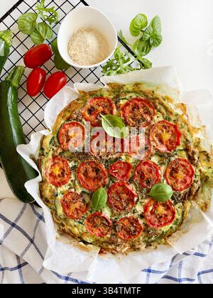 Hausgemachte, im Ofen gebackene Frittata mit Gemüse wie Zucchini, Tomaten, Eiern und Basilikum. Gesunde Ernährung. Sommeressen. Direkt darüber. Stockfoto