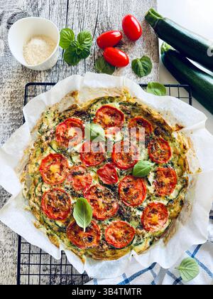 Hausgemachte, im Ofen gebackene Frittata mit Gemüse wie Zucchini, Tomaten, Eiern und Basilikum. Gesunde Ernährung. Sommeressen. Direkt darüber. Stockfoto