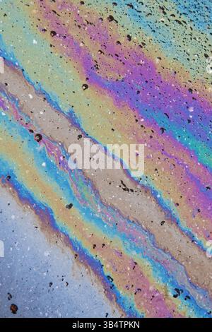 Farbe der Benzinflecken auf Asphalt Road als Textur oder Hintergrund. Irisierende Benzinflecken. Vertikal. Stockfoto
