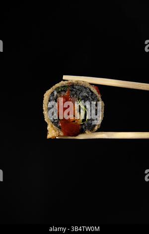 Asiatisches Sushi auf schwarzem Hintergrund in der Hand. Stockfoto