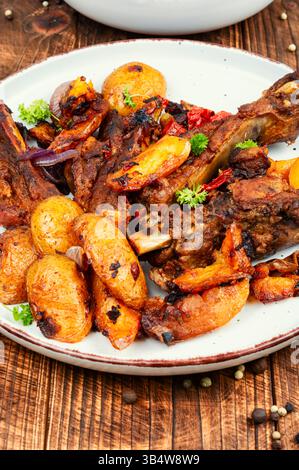 Gebratene Schweinerippchen und Kartoffeln auf rustikalem Holzhintergrund Stockfoto