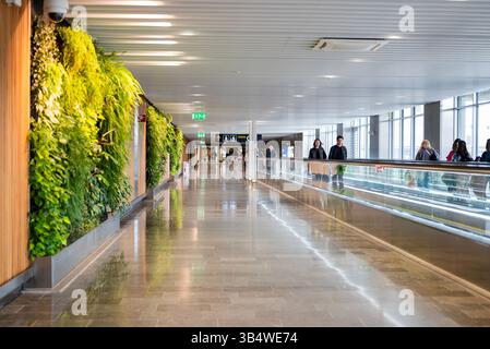 27. April 2025 Stockholm Schweden , Korridordurchfahrt zwischen den Terminals am Flughafen Arlanda mit Rolltreppe und Fluggästen Stockfoto