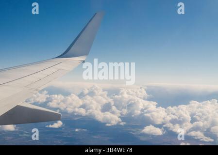 Blick vom Flugzeug auf Flügel im Himmel mit schönen Wolken in Höhe des Fluges Stockfoto