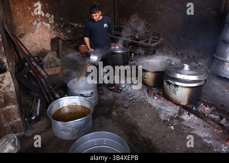 23. April 2022, Rafah, Gazastreifen, Palästina: Palästinenser kochen über Feuer. Suleiman Al-Aloul Madi verwendet seit 50 Jahren Feuer, um Speisen zu kochen, während er Mahlzeiten nach den Wünschen des Kunden zubereitet. Dies hilft ihm auch, die schwierigen Bedingungen im Gazastreifen zu überwinden. (Bild: © Samar Abu Elouf/ZUMA Press Wire Service) Stockfoto
