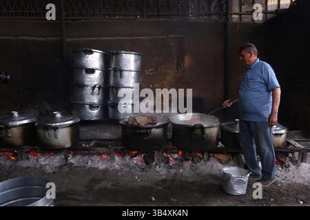 23. April 2022, Rafah, Gazastreifen, Palästina: Palästinenser kochen über Feuer. Suleiman Al-Aloul Madi verwendet seit 50 Jahren Feuer, um Speisen zu kochen, während er Mahlzeiten nach den Wünschen des Kunden zubereitet. Dies hilft ihm auch, die schwierigen Bedingungen im Gazastreifen zu überwinden. (Bild: © Samar Abu Elouf/ZUMA Press Wire Service) Stockfoto