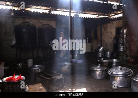 23. April 2022, Rafah, Gazastreifen, Palästina: Palästinenser kochen über Feuer. Suleiman Al-Aloul Madi verwendet seit 50 Jahren Feuer, um Speisen zu kochen, während er Mahlzeiten nach den Wünschen des Kunden zubereitet. Dies hilft ihm auch, die schwierigen Bedingungen im Gazastreifen zu überwinden. (Bild: © Samar Abu Elouf/ZUMA Press Wire Service) Stockfoto