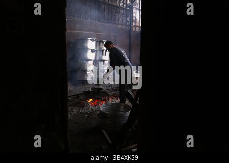 23. April 2022, Rafah, Gazastreifen, Palästina: Palästinenser kochen über Feuer. Suleiman Al-Aloul Madi verwendet seit 50 Jahren Feuer, um Speisen zu kochen, während er Mahlzeiten nach den Wünschen des Kunden zubereitet. Dies hilft ihm auch, die schwierigen Bedingungen im Gazastreifen zu überwinden. (Bild: © Samar Abu Elouf/ZUMA Press Wire Service) Stockfoto