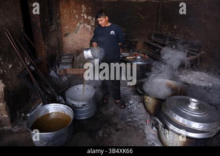 23. April 2022, Rafah, Gazastreifen, Palästina: Palästinenser kochen über Feuer. Suleiman Al-Aloul Madi verwendet seit 50 Jahren Feuer, um Speisen zu kochen, während er Mahlzeiten nach den Wünschen des Kunden zubereitet. Dies hilft ihm auch, die schwierigen Bedingungen im Gazastreifen zu überwinden. (Bild: © Samar Abu Elouf/ZUMA Press Wire Service) Stockfoto