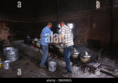 23. April 2022, Rafah, Gazastreifen, Palästina: Palästinenser kochen über Feuer. Suleiman Al-Aloul Madi verwendet seit 50 Jahren Feuer, um Speisen zu kochen, während er Mahlzeiten nach den Wünschen des Kunden zubereitet. Dies hilft ihm auch, die schwierigen Bedingungen im Gazastreifen zu überwinden. (Bild: © Samar Abu Elouf/ZUMA Press Wire Service) Stockfoto