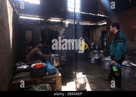 23. April 2022, Rafah, Gazastreifen, Palästina: Palästinenser kochen über Feuer. Suleiman Al-Aloul Madi verwendet seit 50 Jahren Feuer, um Speisen zu kochen, während er Mahlzeiten nach den Wünschen des Kunden zubereitet. Dies hilft ihm auch, die schwierigen Bedingungen im Gazastreifen zu überwinden. (Bild: © Samar Abu Elouf/ZUMA Press Wire Service) Stockfoto