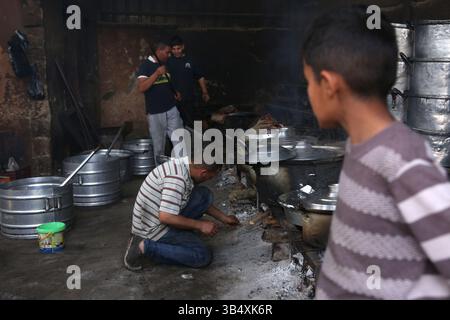 23. April 2022, Rafah, Gazastreifen, Palästina: Palästinenser kochen über Feuer. Suleiman Al-Aloul Madi verwendet seit 50 Jahren Feuer, um Speisen zu kochen, während er Mahlzeiten nach den Wünschen des Kunden zubereitet. Dies hilft ihm auch, die schwierigen Bedingungen im Gazastreifen zu überwinden. (Bild: © Samar Abu Elouf/ZUMA Press Wire Service) Stockfoto