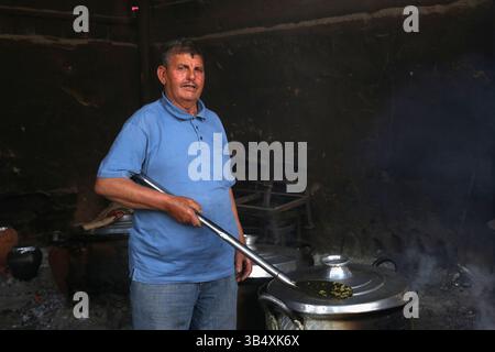 23. April 2022, Rafah, Gazastreifen, Palästina: Palästinenser kochen über Feuer. Suleiman Al-Aloul Madi verwendet seit 50 Jahren Feuer, um Speisen zu kochen, während er Mahlzeiten nach den Wünschen des Kunden zubereitet. Dies hilft ihm auch, die schwierigen Bedingungen im Gazastreifen zu überwinden. (Bild: © Samar Abu Elouf/ZUMA Press Wire Service) Stockfoto