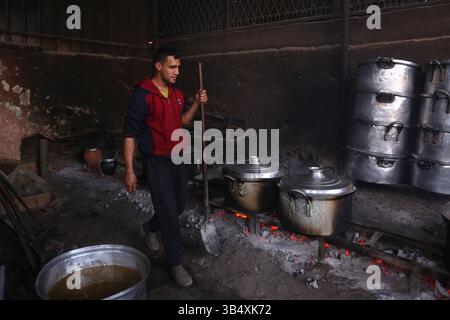 23. April 2022, Rafah, Gazastreifen, Palästina: Palästinenser kochen über Feuer. Suleiman Al-Aloul Madi verwendet seit 50 Jahren Feuer, um Speisen zu kochen, während er Mahlzeiten nach den Wünschen des Kunden zubereitet. Dies hilft ihm auch, die schwierigen Bedingungen im Gazastreifen zu überwinden. (Bild: © Samar Abu Elouf/ZUMA Press Wire Service) Stockfoto