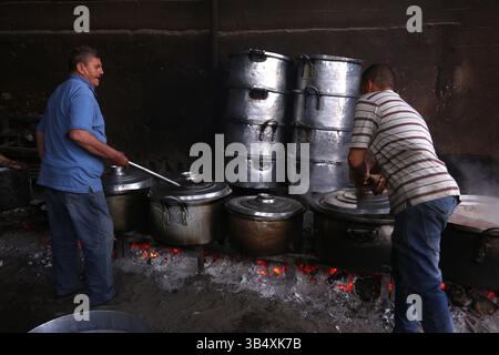 23. April 2022, Rafah, Gazastreifen, Palästina: Palästinenser kochen über Feuer. Suleiman Al-Aloul Madi verwendet seit 50 Jahren Feuer, um Speisen zu kochen, während er Mahlzeiten nach den Wünschen des Kunden zubereitet. Dies hilft ihm auch, die schwierigen Bedingungen im Gazastreifen zu überwinden. (Bild: © Samar Abu Elouf/ZUMA Press Wire Service) Stockfoto