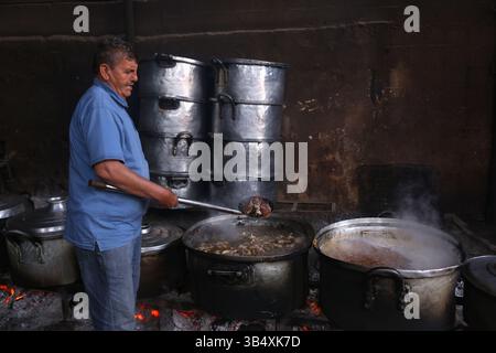 23. April 2022, Rafah, Gazastreifen, Palästina: Palästinenser kochen über Feuer. Suleiman Al-Aloul Madi verwendet seit 50 Jahren Feuer, um Speisen zu kochen, während er Mahlzeiten nach den Wünschen des Kunden zubereitet. Dies hilft ihm auch, die schwierigen Bedingungen im Gazastreifen zu überwinden. (Bild: © Samar Abu Elouf/ZUMA Press Wire Service) Stockfoto