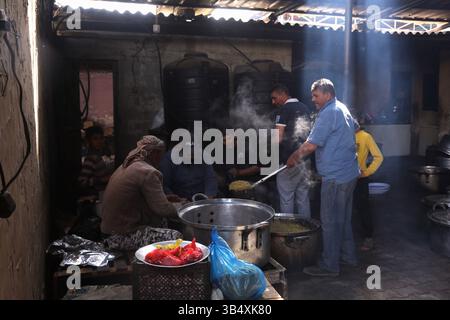 23. April 2022, Rafah, Gazastreifen, Palästina: Palästinenser kochen über Feuer. Suleiman Al-Aloul Madi verwendet seit 50 Jahren Feuer, um Speisen zu kochen, während er Mahlzeiten nach den Wünschen des Kunden zubereitet. Dies hilft ihm auch, die schwierigen Bedingungen im Gazastreifen zu überwinden. (Bild: © Samar Abu Elouf/ZUMA Press Wire Service) Stockfoto