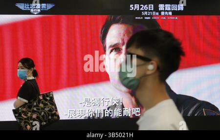 18. Mai 2022, HONGKONG, CHINA: Maskierte Bürger gehen an einer Großleinwand in der MTR Station in Hongkong vorbei und zeigen den Trailer von Coming American Mega Movie TOP GUN Maverick mit Tom Cruise in der Hauptrolle. Nach großer Erwartung und zwei Jahren Verzögerung aufgrund der COVID-19-Pandemie, die 2020 in China ausbrach und sich auf die Welt ausbreitete, die die Weltpremiere unterbrach, findet am 26. Mai dieses Jahres die Premiere von Hollywood Mega Movie, TOP GUN - Maverick Hong Kong in der Pest betroffenen Stadt statt.Mai-18.2022Hong Kong.ZUMA/Liau Chung-ren (Kreditbild: © Liau Chung-ren/ZUMA Press Wire) Stockfoto