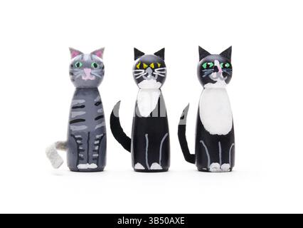 Drei Katzenfiguren auf weißem Hintergrund. Gruppe von Miniatur-Katzenstatuen, die in die Kamera schauen. Niedliche, handgemachte Katzenkatzen aus Holzstiften. Tabby und 2 Stockfoto