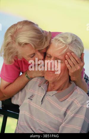 Senior Mann und Frau schließen sich draußen sitzen. Stockfoto