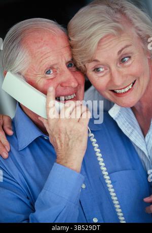 Nahaufnahme eines älteren Mannes und einer Frau drinnen, die am Telefon sprachen. Stockfoto