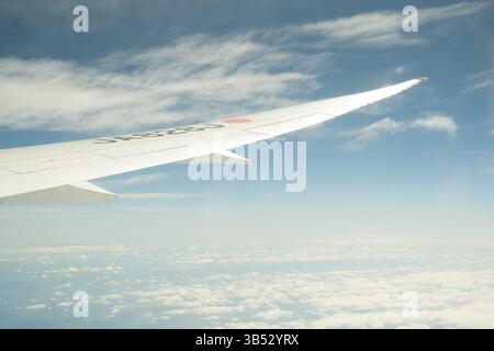 Helle Sicht auf den Flugzeugflügel und Wolken vom Passagiersitz während des Fluges Stockfoto