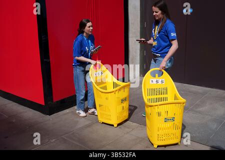 Während der Eröffnung des neuen Flagship-Stores der schwedischen Home- und Lifestyle-Marke IKEA am Oxford Circus im West End am 1. Mai 2025 in London, England, ziehen die Mitarbeiter Einkaufskörbe entlang der Oxford Street. Stockfoto