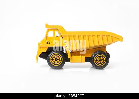 Ein gelber Spielzeugkipper mit detaillierten Rädern und einem schlichten Design auf weißem Hintergrund. Stockfoto