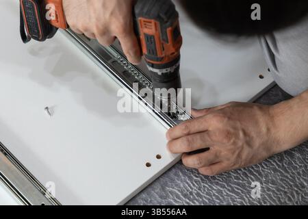 Nahaufnahme eines Mannes mit einem Schraubenzieher, um zu Hause eine Garderobe zu bauen. Häusliche Atmosphäre und Alltagskonzept Stockfoto