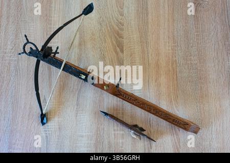 Dekorative Holzarmbrust mit Pfeil auf einem Tisch von oben gesehen Stockfoto