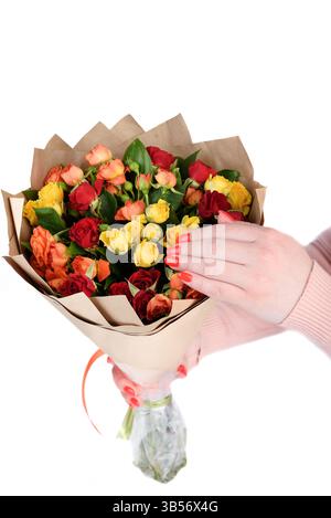 Weibliche Hände mit einem umwickelten Blumenstrauß aus mehrfarbigen Rosen. Florismusarbeit. Stockfoto