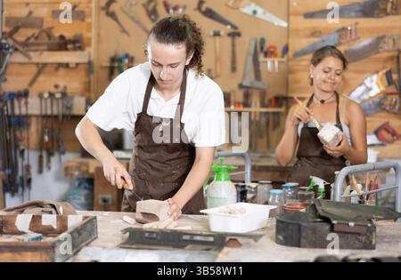 Der Kerl ist in einer Tischlerei mit einer Unternehmerin beschäftigt Stockfoto
