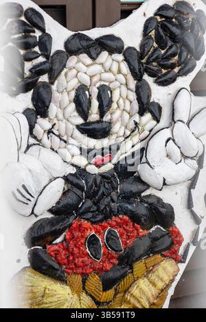 ALBUFEIRA, PORTUGAL - 9. NOVEMBER 2024: Nahaufnahme einer Sammlung von Kunstwerken von Mickey-Maus, die mit Muscheln verkrustet ist. Stockfoto