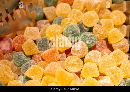 Ein lebhaftes Sortiment an gummiartigen Bonbons in verschiedenen Formen und Farben befindet sich in einem offenen Marktstand. Die zuckersüßen Süßigkeiten funkeln unter Sonnenlicht, A Stockfoto