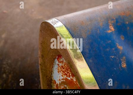 Nahaufnahme eines rostigen Rücklichts eines klassischen Rennwagens mit blauer Farbe und Chromverzierungen, das Vintage-Styling und verwitterte Fahrzeugdetails zeigt. Stockfoto