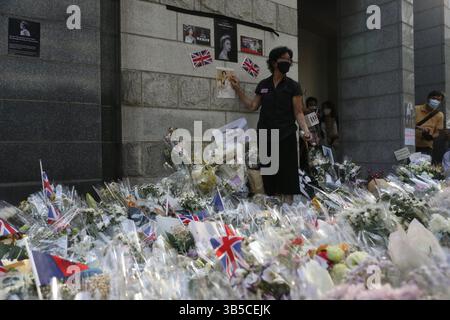 12. September 2022, HONGKONG, CHINA: Eine Frau gibt Gesten vor dem provisorischen „ Altar “ voller Blumen vor dem britischen Generalkonsulat Hongkong.Sept-12.2022Hongkong.ZUMA/Liau Chung-ren (Kreditbild: © Liau Chung-ren/ZUMA Press Wire) Stockfoto