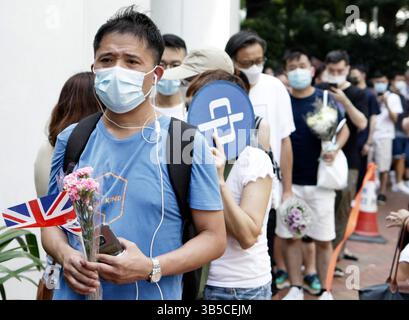 12. September 2022, HONGKONG, CHINA: Ein Mann aus Hongkong hält den kleinen Union Jack und den Blumenstrauß, während er sich vor dem britischen Generalkonsulat in Hongkong anstellt, um der verstorbenen britischen Königin Elizabeth II. September 2022 zu ehren. Hongkong.ZUMA/Liau Chung-ren (Foto: © Liau Chung-ren/ZUMA Press Wire) Stockfoto