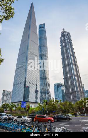 Shanghai, China - 1. April 2025: Shanghai Tower, Jinmao Tower und SWFC durchdringen den Dämmerungshimmel, während der abendliche Verkehr darunter fließt Stockfoto