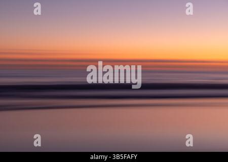 Traumhafter heller Sonnenuntergang über verschwommenem Horizont der Küste - ICM Yellow and Purple Stockfoto