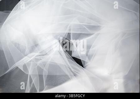 Dies ist ein Nahbild eines zarten weißen Schleiers, der ein auffallendes Loch im Gewebe aufweist und eine einzigartige visuelle Textur erzeugt Stockfoto