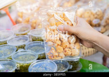 Traditionelle frittierte Schweinehaut auf Frauenhand. Berühmtes Beilagenmenü im Asia Restaurant. Knuspriges und knuspriges Snackkonzept. Stockfoto