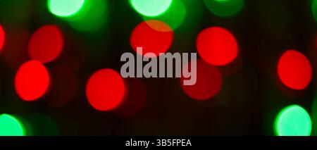 Abstrakter Hintergrund mit beleuchteten Bokeh-Kreisen, leuchtenden roten und grünen Weihnachtslichtern Stockfoto