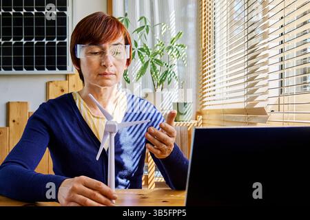 Geschäftsfrau mit Augmented-Reality-Brille Analyse Windturbinenmodell im Heimbüro in der Erneuerbare-Energien-Industrie. Stockfoto