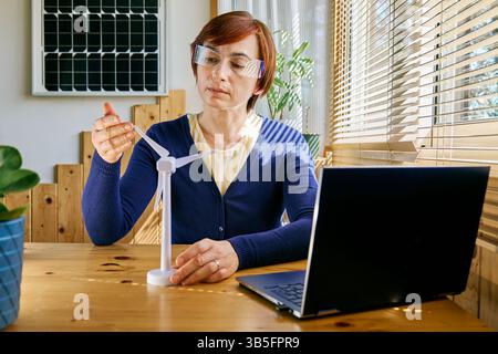 Geschäftsfrau mit Augmented-Reality-Brille Analyse Windturbinenmodell im Heimbüro in der Erneuerbare-Energien-Industrie. Stockfoto