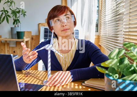 Geschäftsfrau mit Augmented-Reality-Brille Analyse Windturbinenmodell im Heimbüro in der Erneuerbare-Energien-Industrie. Stockfoto