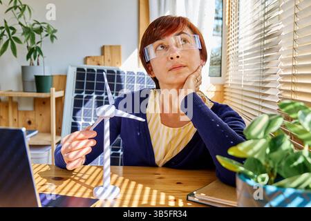 Geschäftsfrau mit Augmented-Reality-Brille Analyse Windturbinenmodell im Heimbüro in der Erneuerbare-Energien-Industrie. Stockfoto